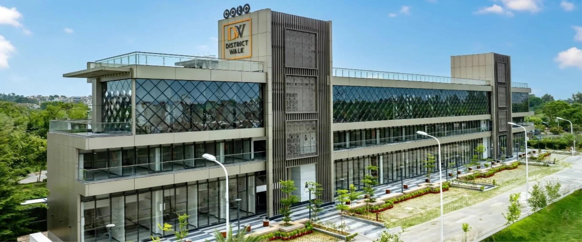 Front view of BPTP District Walk's contemporary commercial complex in Sector 81, Faridabad, showcasing its sleek glass facade and landscaped surroundings