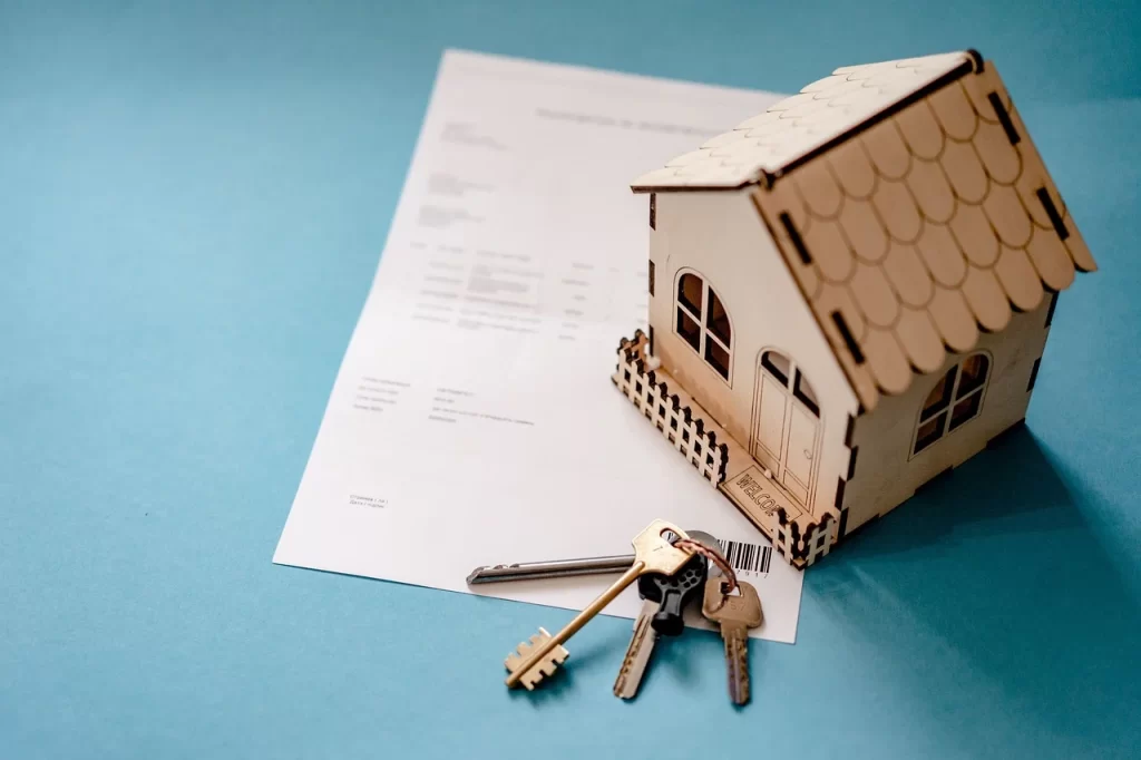 Model house placed on property documents with house keys, symbolizing real estate ownership, home buying, or property registration process